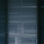 A vertical interior shot of closed window blinds creating a moody atmosphere.
