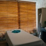 A tranquil massage room with natural light and neatly arranged furnishings for relaxation.