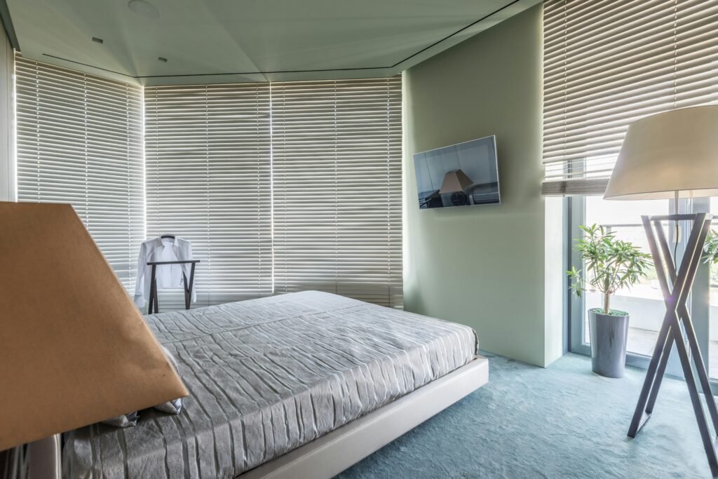 A cozy minimalist bedroom featuring neutral decor, large windows, and abundant natural light.